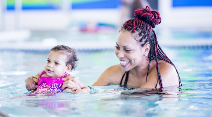 swimming and water safety; mother holds infant in pool