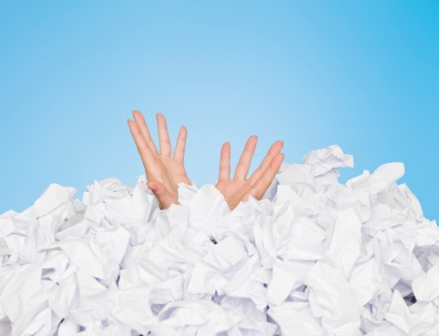 Human buried in white papers on blue background; drowning in papers